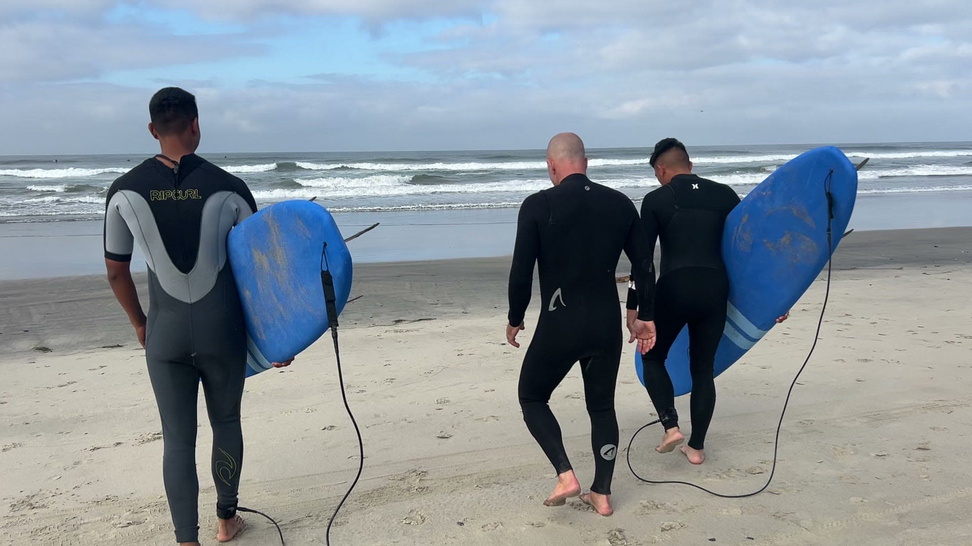 Boards under arms, walking into the Pacific — surf ministry morning